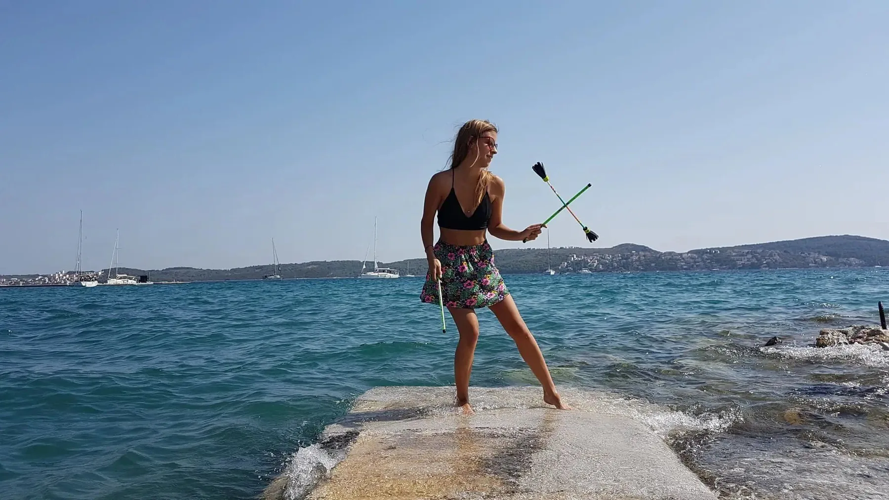Girl playing a flower stick on a pier by the sea